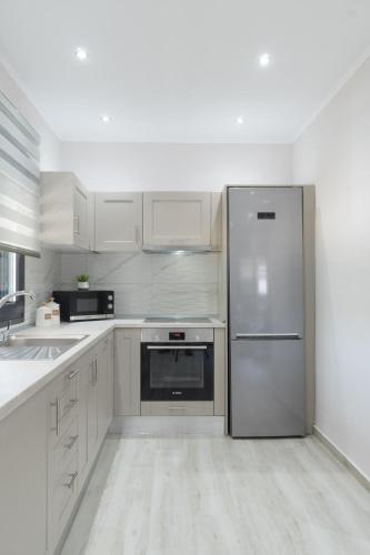 a kitchen with stainless steel refrigerator and white cabinets at LUXURY VILLAS ELENI STEFI in Limenas