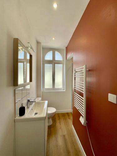 une salle de bain avec un lavabo et des toilettes et une fenêtre dans l'établissement Maison familiale proche centre ville, à Amiens