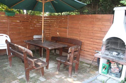 a wooden table and chairs with an umbrella and a grill at Ugeni ,apartament in Ostrowo