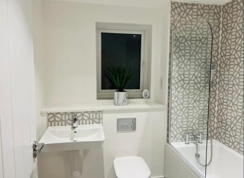 baño con lavabo y aseo y ventana en Stylish new built double bed, en Mánchester