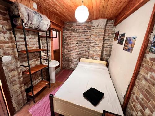 a bedroom with a bed in a room with a brick wall at Rooms Nesti INSIDE OF CASTLE in Krujë
