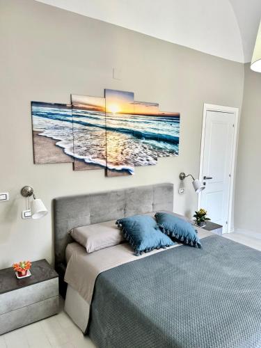 a bedroom with a bed with three paintings on the wall at B&B La Reggia del Sol in Trani