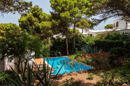 a swimming pool in a garden with trees and flowers at Villa Menorca Ses Roques Vermelles by Mauter Villas in Cala Morell