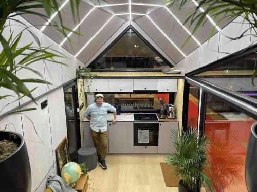 a man standing in the kitchen of a tiny house at Storjord Farmstay Glamping in Tromsø