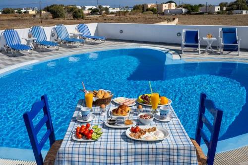 a table with plates of food next to a swimming pool at Irene's Sunshine Studio in Perivolos