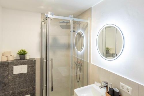 a bathroom with a shower and a sink and a mirror at Hotel BUTZ in Scharbeutz