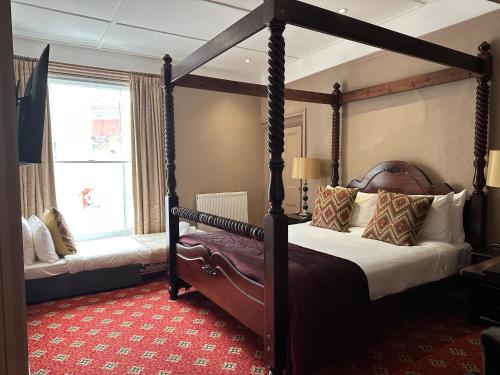 een slaapkamer met een hemelbed en een raam bij The Tudor Hotel in Bridgwater