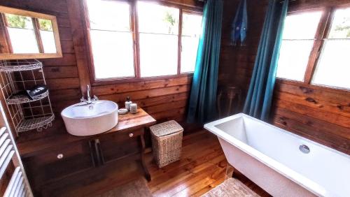 ein Bad mit einer Badewanne, einem Waschbecken und Fenstern in der Unterkunft Chalet TanZanTan in La Plaine des Palmistes