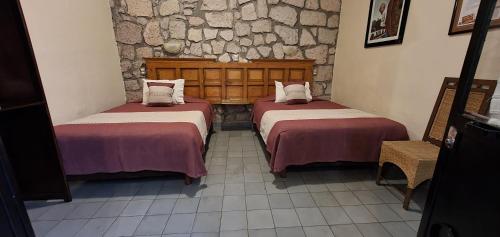 two beds in a room with a stone wall at ROSA BARROCO in Morelia