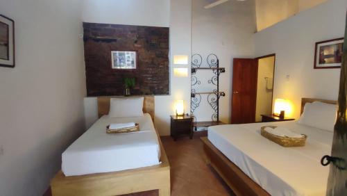 a bedroom with two beds and two tables and two lamps at HOTEL NIETO MOMPOX, ubicado en el corazón del centro histórico, frente al rio magdalena en zona de malecón in Mompos