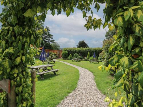 a garden with picnic tables and a gravel path at Pansi in Welshpool