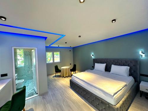 een slaapkamer met een bed met een blauwe muur bij Breezy Hotel in Valbonë