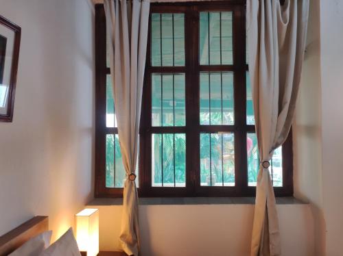 a window with curtains in a room with a light at HOTEL NIETO MOMPOX, ubicado en el corazón del centro histórico, frente al rio magdalena en zona de malecón in Mompos