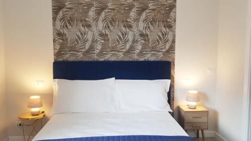 a bedroom with a bed with a blue headboard and two lamps at Lorixedda Rooms in Quartu SantʼElena