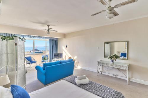 a bedroom with a blue couch and a blue chair at 3 Sandringham Sea Facing ground-floor Studio in Cape Town