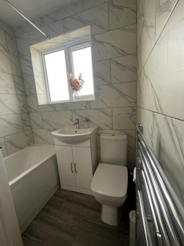 a bathroom with a toilet and a sink and a window at Beautiful house/Parking in Plumstead
