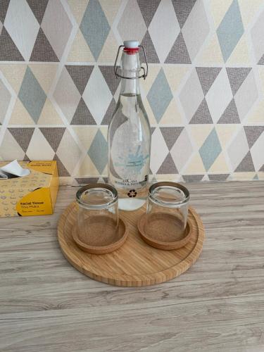 uma garrafa e dois copos num tabuleiro de madeira em Ariana Roomstay @ skyloft em Johor Bahru