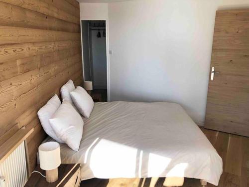 une chambre avec un lit avec des draps blancs et des oreillers dans l'établissement 3 pièces, 6 personnes, à Chamrousse