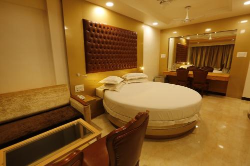 a bedroom with a large bed and a table and chairs at Hotel Ravikiran Alibaug in Alibaug