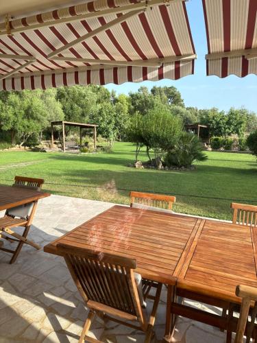 a wooden table and chairs under an umbrella on a patio at Villa Arzilla Sardegna in Alghero