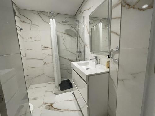 a white bathroom with a sink and a mirror at Estudio Balaia by Villas Key in Albufeira