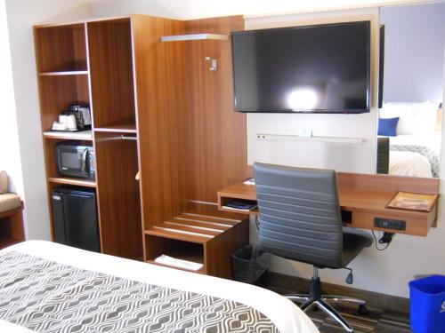 a hotel room with a desk with a computer and a television at Microtel Inn & Suites Sault Ste. Marie in Sault Ste. Marie
