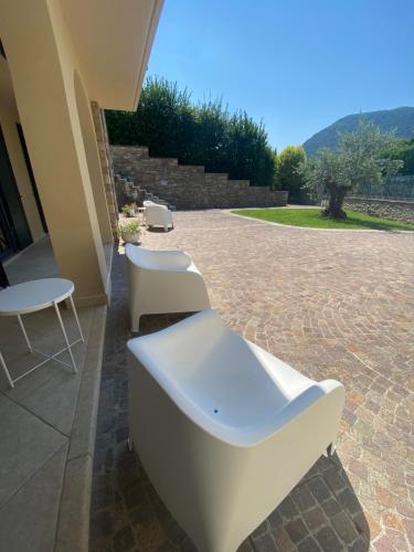 a patio with two white chairs and a table at Vela di Soleville camere con e senza vista lago con ristorante & pizzeria in Sale Marasino