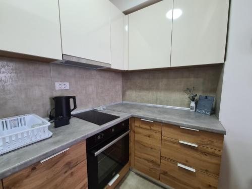 een keuken met witte kasten, een wastafel en een fornuis bij Skopje Center City Apartment 3 in Skopje