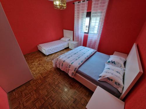 1 dormitorio rojo con 2 camas y ventana en Apartment Dragovic, en Ulcinj