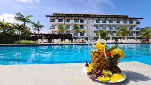 un plato de fruta junto a la piscina en Flat 402 Laguna Beach - tipo Loft encantador, mobiliado e aconchegante en Porto de Galinhas