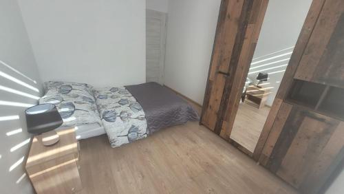 a small bedroom with a bed and a wooden floor at Apartament "Cztery Pory Roku" in Świdnik