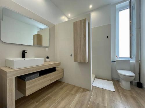 ein Badezimmer mit einem Waschbecken, einem WC und einem Spiegel in der Unterkunft Le Varsovie ※ 4 balcons in Carcassonne