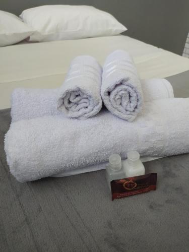 una pila de toallas y una botella de jabón en una cama en Quarto privativo no centro 02, en Itapira