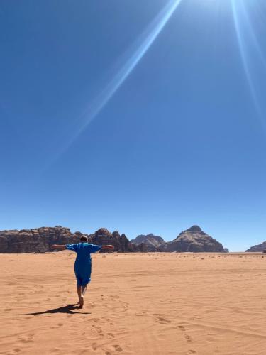 a man walking on the beach with his arms outstretched at Desert's Soul Wadi Rum in Disah