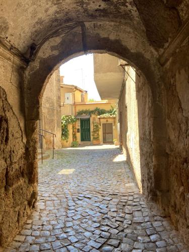 une allée en pierre avec une arche dans un bâtiment dans l'établissement Platea Cavour, à Sutri