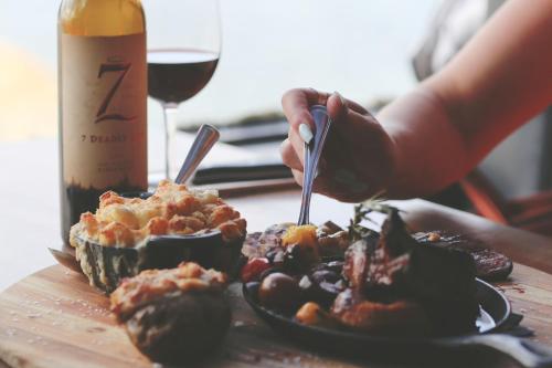 a person eating food on a table with a glass of wine at Oceanfront Suites at Cowichan Bay in Cowichan Bay