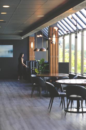a woman standing in a room with tables and chairs at Oceanfront Suites at Cowichan Bay in Cowichan Bay