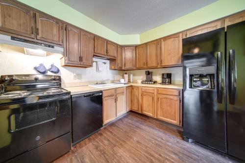 a kitchen with a black refrigerator and wooden cabinets at Cleveland Area Retreat Near Lake Erie in Richmond Heights