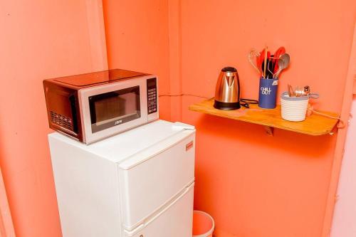 a microwave sitting on top of a refrigerator at Negril's Hidden Gem With Modern Amenities in Negril