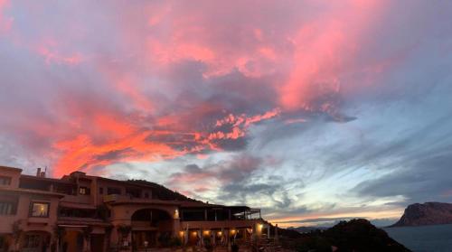 a cloudy sky at sunset with a building at SAN TEODORO PUNTA EST SPETTACOLARE QUADRILOCALE VISTA MARE in Capo Coda Cavallo