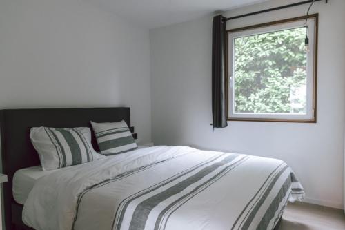 1 dormitorio con 1 cama grande y ventana en Imagine Tiny House 325 op Camping GT te Balen, en Balen