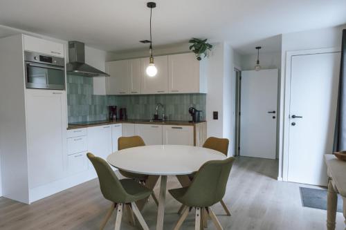 a kitchen with a white table and green chairs at Imagine Tiny House 325 op Camping GT te Balen in Balen