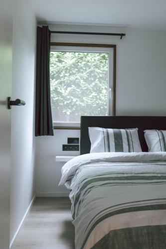 a bedroom with a bed and a window at Imagine Tiny House 325 op Camping GT te Balen in Balen