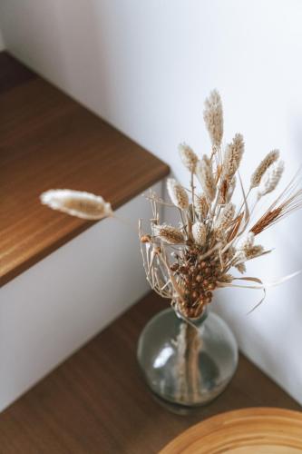 a glass vase with dried flowers in it on a table at Imagine Tiny House 325 op Camping GT te Balen in Balen