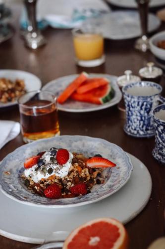 a table with a plate of food with fruit and whipped cream at Arosfa Harbourside Aberaeron in Aberaeron