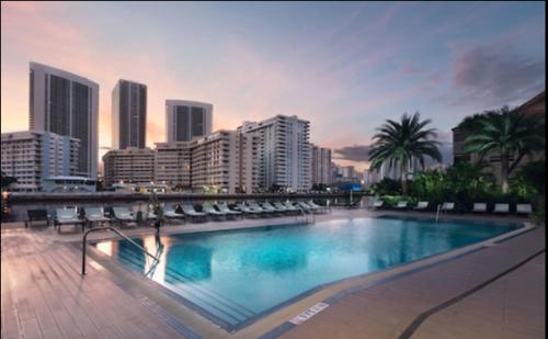 Una gran piscina en una ciudad con edificios. en Modern Studio Escape at BeachWalk, Perfect for Small Groups -B, en Hallandale Beach