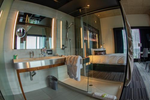 a bathroom with a sink and a shower and a bed at Grand Times Hotel Drummondville in Drummondville