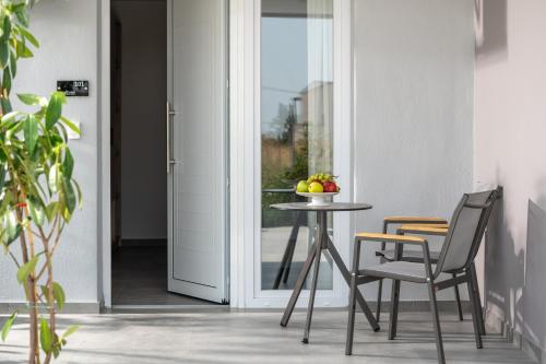 a table and chairs next to a door with a bowl of fruit at Calives Premium Stay in Kalyves Poligirou