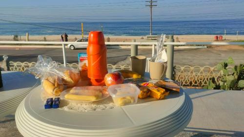 馬里卡的住宿－Suítes Pé Nareia Itaipuaçu，一张桌子上摆着的盘子,享有海滩美景