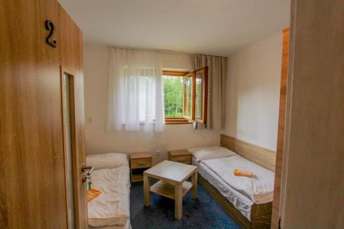 a small room with two beds and a window at Chata Biela Stopa in Vysoke Tatry - Tatranska Lomnica.